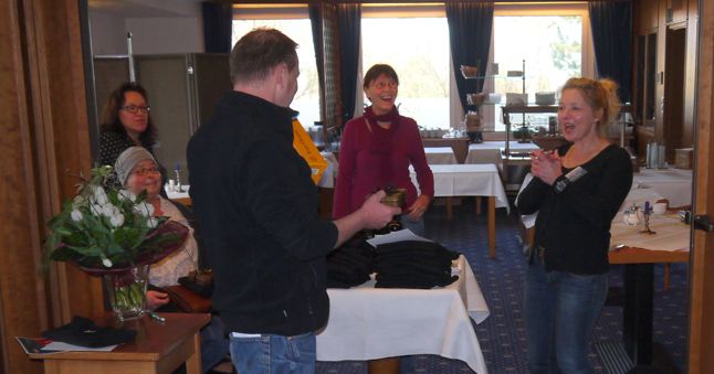 In dieser Szene während einer Siegerehrung sind Britta und Suanne zu sehen. Susanne steht und nimmt eine Flasche Champagner entgegen. Susanne sitzt links im Bild.
